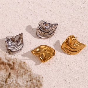 Detailed macro shot showing gold and silver irregular wave textured metal stud earrings