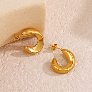 Boucles d'oreilles créoles creuses en C dorées 18K sur fond beige texturé élégant