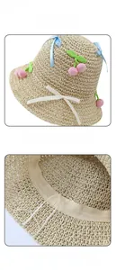 Detailed view of handmade straw sun hat with pink cherry crochet and bow tie decoration