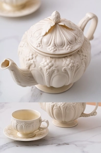 Close-up of vintage embossed ceramic teapot, cup and saucer set in creamy white finish
