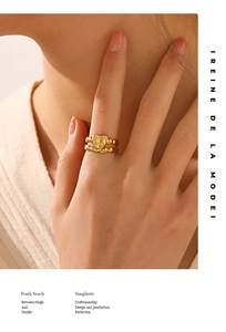 Close-up of a gold heart ring with a beaded band worn on a finger for a stylish look
