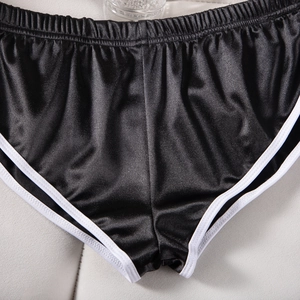 Dettaglio di pantaloncini sportivi neri in raso liscio con bordi a contrasto bianchi