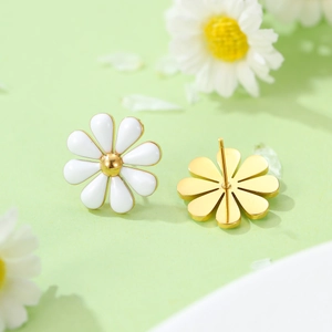 Detail of daisy stud earrings with white petals and gold core on green background