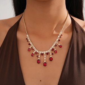 Detail of vintage gold necklace featuring a red emerald-cut stone with fringe accents