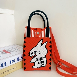 Detail of orange knitted crossbody bag with cartoon rabbit and SHUT UP text