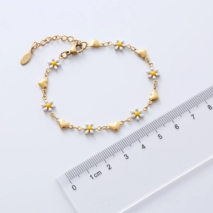 Detail of 18k gold plated daisy and heart bracelet with stainless steel logo tag and ruler