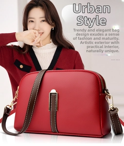 Detail of red litchi leather crossbody bag with golden buckle and brown shoulder strap