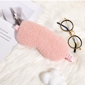 Detail of pink teddy plush sleep mask with silk elastic strap on a soft white background