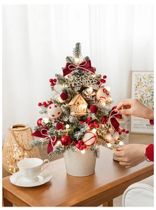 Close-up of DIY mini Christmas tree with warm LED lights and red ornaments in a white pot