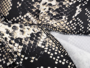 Detailed view of the black and yellow snakeskin pattern on silk-satin midi skirt fabric