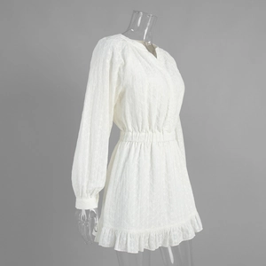 Détail de la robe blanche brodée montrant la taille élastique et l'ourlet volanté