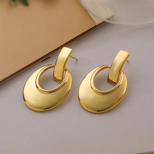 Macro detail of geometric hollow oval earrings in a polished 18K gold metallic finish