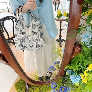 Detail of canvas bag with butterfly print and woven handle in a soft cafe setting