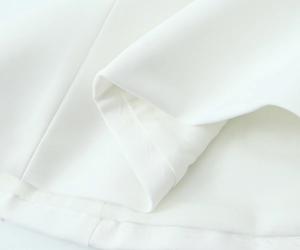 Close-up of white stretch fabric showing plain weave texture and reinforced stitching detail