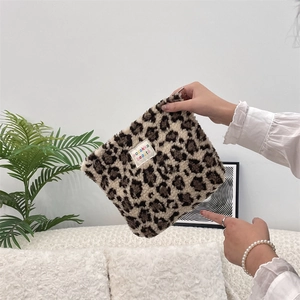 Detailed view of plush leopard print makeup bag with woven brand label and soft texture