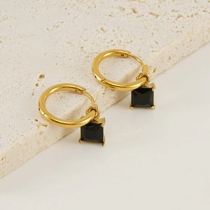 Détail de créoles en acier doré 18K avec pampilles en zircon noir de forme carrée