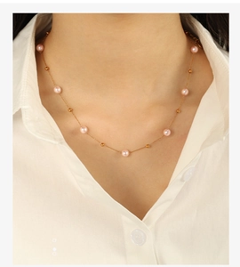 Macro detail of 18K gold necklace featuring pink pearls and small golden beads on neck