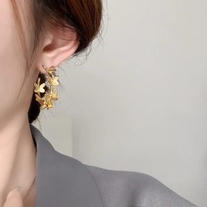 Detailed close-up of a gold-plated butterfly earring worn by a model in a side profile view