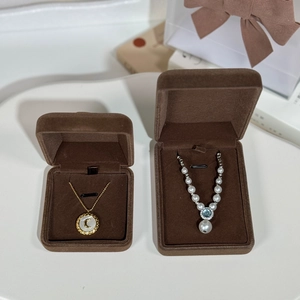 Close-up of golden moon and blue gemstone necklaces in brown velvet jewelry boxes