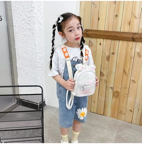 White PU leather kids backpack with sequins and bow details worn by a young model