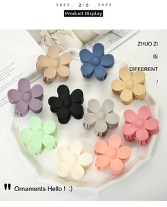 Flat lay of 10 matte flower hair claws in Morandi colors displayed on a white plate