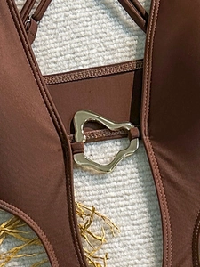 Detailed macro view of the golden heart-shaped metal buckle on a brown one-piece swimsuit
