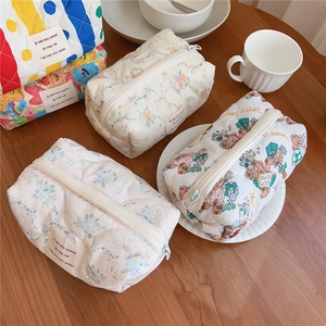 Close-up of quilted cotton cosmetic bags with bear and floral prints on a wooden table
