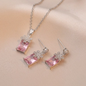 Pink rectangular gemstone necklace and earring set with floral accents on satin