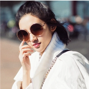 Detail of round metal sunglasses with brown gradient lenses and hollow frame on model