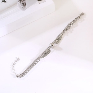 Detail of silver double-layered chain bracelet with angel wings and sphere pendant
