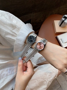 Detail of elegant ladies' watches with diamond indices and metallic bracelets on wrist
