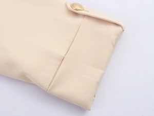 Detail view of beige suit sleeve cuff featuring a textured gold button finish