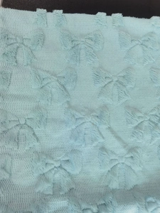 Close-up of light blue plush fabric with a soft embossed bow texture for sofa pillows