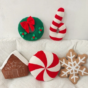 Christmas plush pillow set including wreath candy cane and gingerbread house on a sofa
