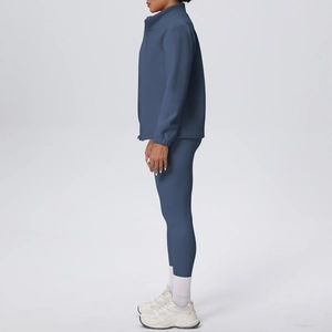 Vista laterale di una donna in completo yoga blu scuro con giacca e leggings a vita alta