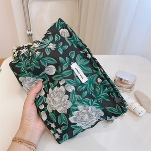 Detail of floral jacquard cosmetic bag featuring a leaf pattern and a zipper closure