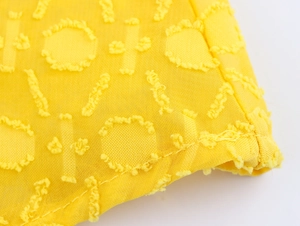 Makroaufnahme von gelbem Strukturstoff mit 3D-Blumenstickerei und feinen Nähten
