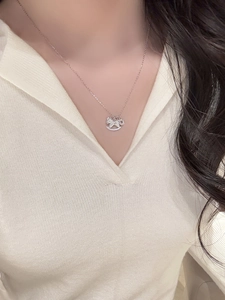 Gros plan d'un collier en argent avec un pendentif cheval à bascule en zircon.