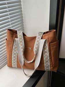 Borsa tote in tela marrone con spalline a motivi e tasche laterali su un davanzale