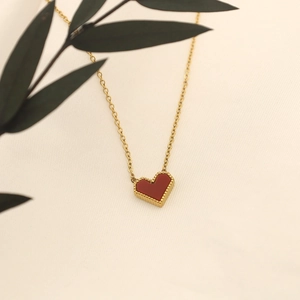 Detail of red heart necklace with gold beads on elegant fabric background