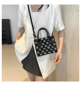Detail of checkered woven handbag with fringe trim and detachable black shoulder strap