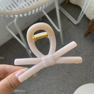 Detailed close-up of pink bow hair claw clip showing the inner golden metal spring mechanism