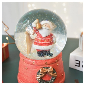 Close-up of Santa Claus snow globe with reindeer, golden glitter, and red carved base