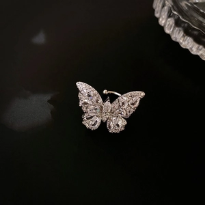 Dettaglio macro di earcuff a farfalla in argento con zirconi lucidi su sfondo nero