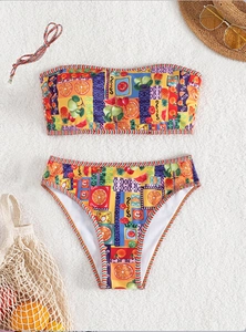 Flachbild-Bikini mit buntem tropischem Fruchtdruck, Strohhut und Strandaccessoires