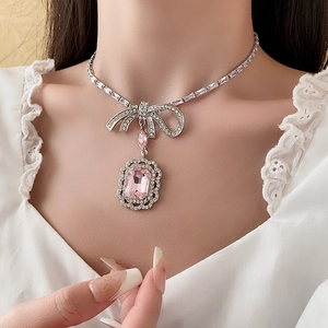 Gros plan d'un collier nœud en argent avec cristal rose rectangulaire et brillants