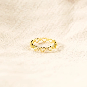 Bague coeur doré évidé avec bords milgrain et zircons sur tissu beige doux