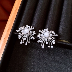 Macro detail of firework-style earrings with pearls and zircons in a black velvet box