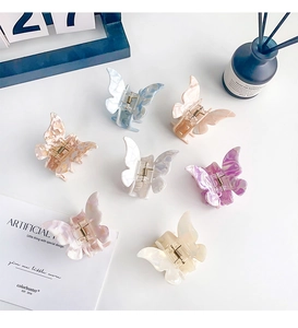 Detailed top view of 7 colorful marbled acetate butterfly hair clips on a white background