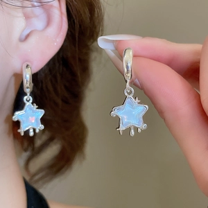 Detailed close-up of a silver star pendant earring with sparkling iridescent resin and diamonds
